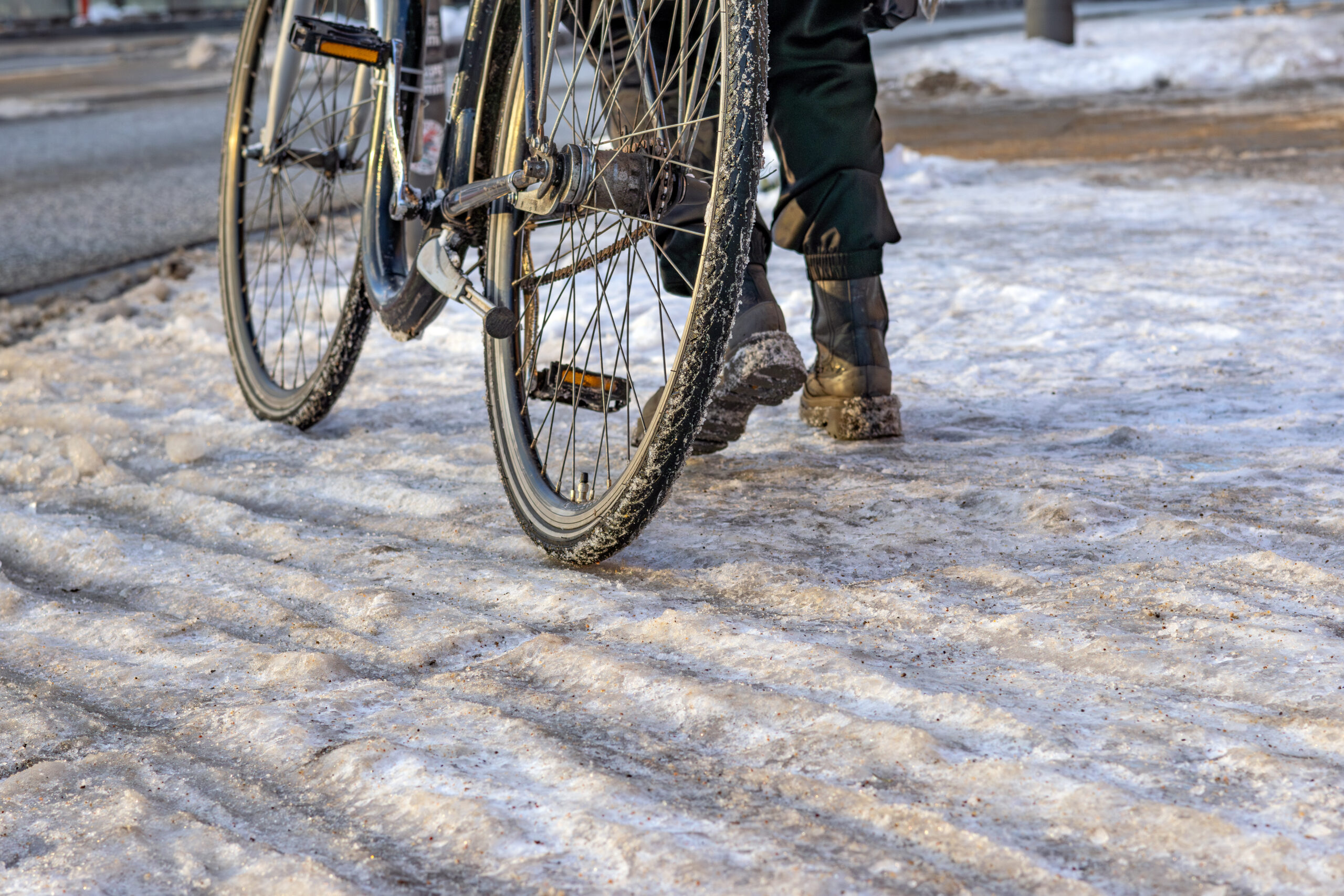 Person pushing bike on icy ground.